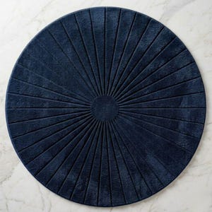 May include: A circular navy blue rug featuring a textured sunburst pattern with raised lines radiating from a solid center circle to the outer edge. The rug has a soft, plush appearance and a consistent deep blue color throughout its surface.