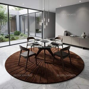 May include: A round, dark brown area rug with a sunburst-style radial pattern, placed under a glass-topped dining table with four dark wood chairs. The rug features textured, linear tufted segments radiating from the center outward.