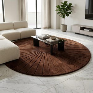 May include: A large, circular, dark brown area rug featuring a textured, sunburst-inspired pattern with radiating lines that extend from a solid center circle toward the outer edge, creating a distinct radial design across the entire surface.