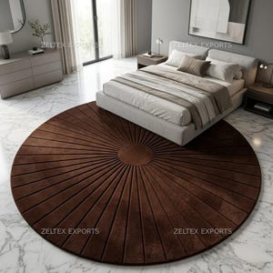 May include: A large, circular, dark brown area rug featuring a sunburst pattern with radiating lines extending from a solid center circle. The rug is placed on a white marble floor, partially positioned underneath a bed with light-colored bedding.