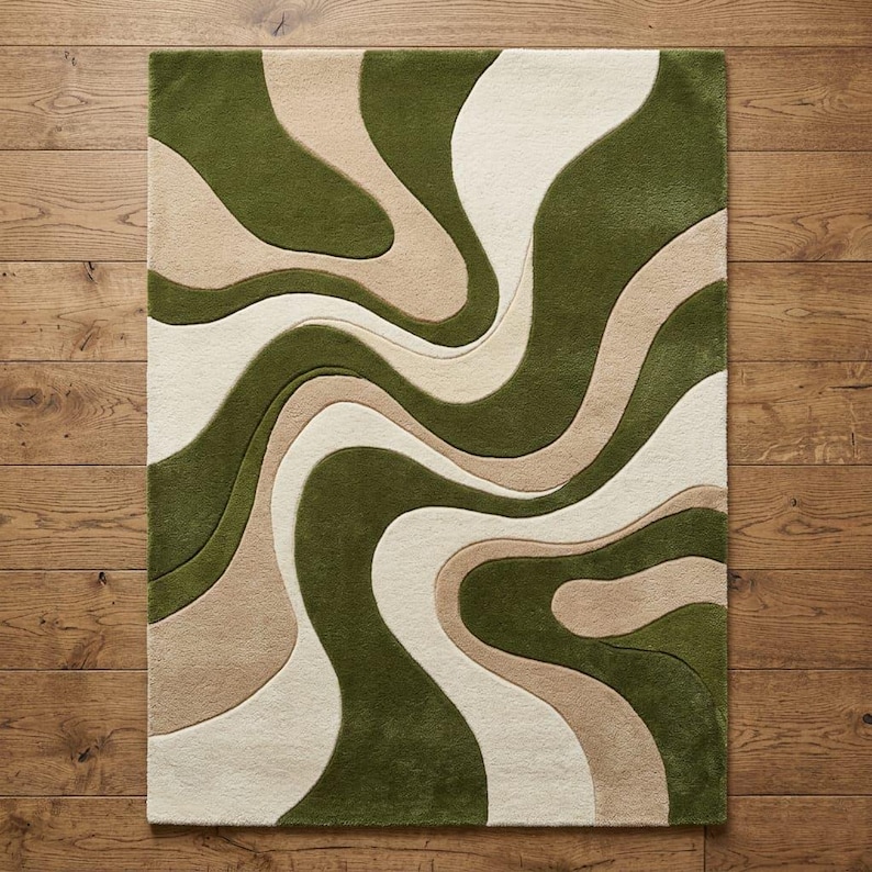 K&ouml;nnte beinhalten: Ein rechteckiger Teppich mit Hochflor-Textur und einem sich wiederholenden Muster aus flie&szlig;enden, organischen Wellenlinien in den Farben tiefes Waldgr&uuml;n, sanftes Beige und Cremewei&szlig;, was einen geschichteten, dreidimensionalen Effekt erzeugt.