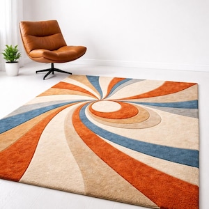 May include: A rectangular area rug with a retro spiral design in shades of orange, blue, beige, and tan. The rug is placed on a white floor, with a brown leather chair and a potted plant in the background.