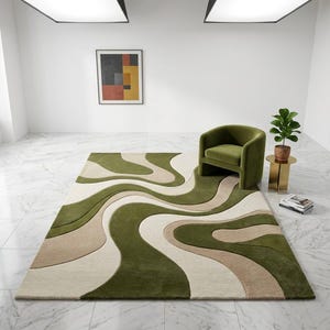 K&ouml;nnte beinhalten: Ein rechteckiger Teppich mit einem wellenf&ouml;rmigen, organischen Muster in Olivgr&uuml;n, Beige und Creme. Der Teppich weist einen strukturierten, mehrstufigen Flor auf, der Tiefe und Dimension auf der gesamten Oberfl&auml;che erzeugt.