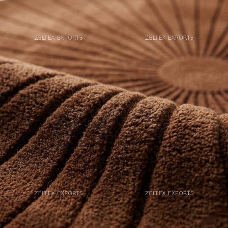 May include: A brown circular rug featuring a textured, tufted surface with a radial sunburst pattern of raised lines radiating from the center. The text ZELTEX EXPORTS is visible in four locations across the surface of the brown fabric material.