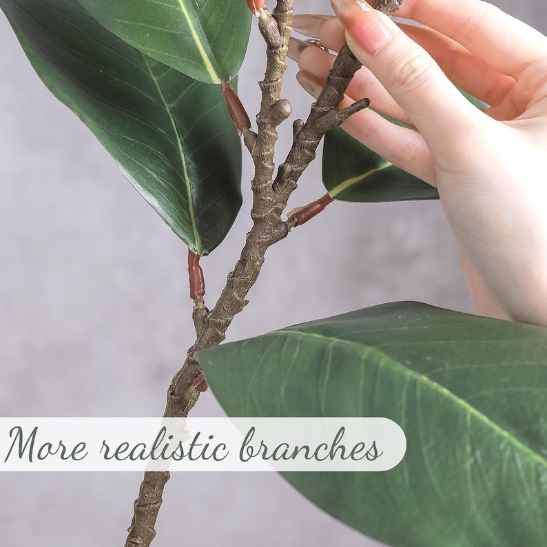 May include: An artificial plant stem featuring dark green, oval-shaped leaves with visible veins and a textured brown branch. The stem includes small reddish-brown nodes at the leaf junctions. The text "More realistic branches" is overlaid.