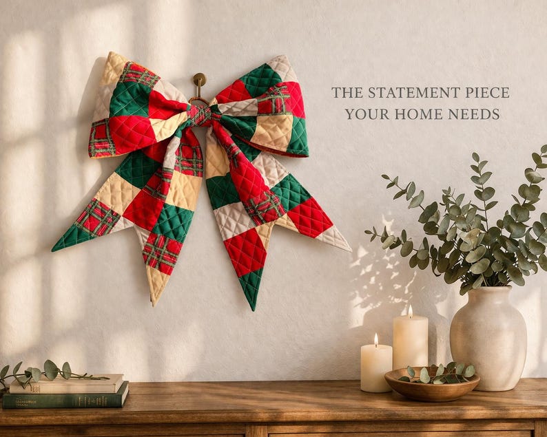 Może przedstawiać: Duża, pikowana kokarda w czerwono-zielono-kremową kratę wisi na ścianie. Kokarda jest centralnym punktem, z tekstem "THE STATEMENT PIECE YOUR HOME NEEDS" po prawej stronie. Drewniany st&oacute;ł mieści świece, wazon z zielenią i książki.