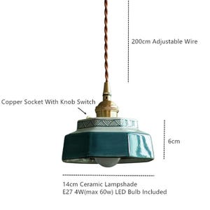 May include: A teal ceramic lampshade with a white and blue patterned rim, suspended by a brown wire. The lamp has a copper socket with a knob switch and includes a 4W LED bulb. The lampshade is 14cm wide and 6cm tall, with a 200cm adjustable wire.