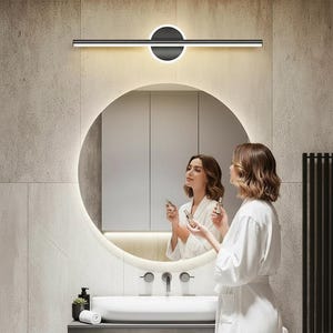 以下が含まれることがあります： モダンな白黒のバスルーム用洗面化粧台ライト。水平バーと円形アクセント、明るい線状光源を備えています。現代的なバスルームの丸い鏡の上に設置されています。