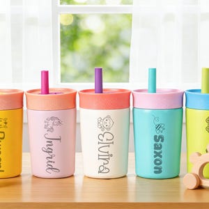 Puede incluir: Cinco vasos personalizados con tapas y pajitas. Cada vaso es de un color diferente: amarillo, rosa, blanco roto, turquesa y verde lima. Cada vaso tiene un nombre y un peque&ntilde;o gr&aacute;fico. Las pajitas y las tapas son de diferentes colores.