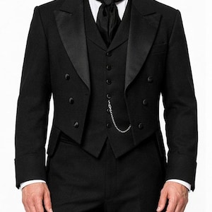 May include: A formal black tuxedo with a notched lapel, double-breasted jacket, and matching vest. The suit includes a white dress shirt, black tie, and a silver chain. The tailored suit is suitable for formal events and special occasions.
