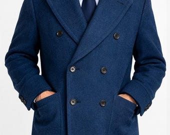 以下が含まれることがあります： ネイビーブルーのダブルブレストコート。コントラストの効いた黒いベルベットの襟が特徴です。大きな黒いボタンと2つのフロントポケットが付いています。白いシャツとネイビーのネクタイを着用しています。