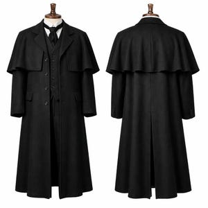 May include: A black wool coat with a cape, vest, and tie, displayed on a mannequin. The coat has a long, flowing design with a button-up front and a notched lapel. The vest has a button-up front and a notched lapel. The tie is black.