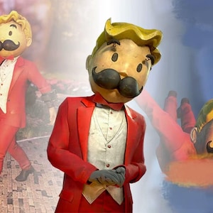 May include: A whimsical figure with a large head, a black mustache, and a red suit. The figure is wearing a white vest and a red bow tie. The background features a path and flowers.