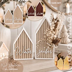 Könnte beinhalten: Ein 14-teiliges Set aus hausförmigen Dekorationsobjekten mit vertikalen Lamellen und weißer Schreibschrift wie Merry, Christmas, Winter und Zauber. Die Häuser sind in Beige und Dunkelrot gehalten, einige mit Trockenblumen verziert.