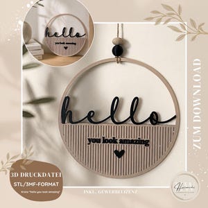 Könnte beinhalten: Runde Wanddekoration aus Holz mit dem Wort "hello" in schwarzer Schrift. Darunter steht der Text "you look amazing" mit einem Herz. Das Design wird von einer Schnur mit Perlen gehalten.