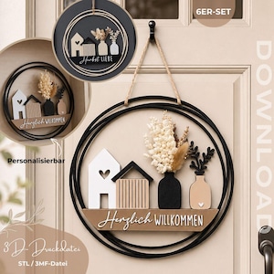 May include: A circular black wall hanging featuring a 3D printed design of two houses, two vases with dried flowers, and a sign with the text Herzlich WILLKOMMEN. The set includes 6ER-SET, DOWNLOAD, and 3D-Druckdatei STL / 3MF-Datei text.