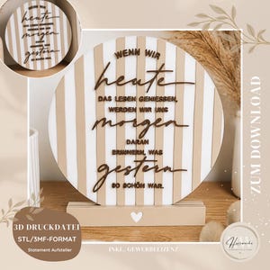 May include: A circular decorative sign featuring vertical beige and white stripes with raised dark brown German text that reads: WENN WIR heute DAS LEBEN GENIESSEN, WERDEN WIR UNS morgen DARAN ERINNERN, WAS gestern SO SCHÖN WAR. It sits on a rectangular base.