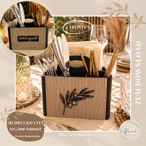 May include: A rectangular cutlery holder with a ribbed light wood exterior and black trim. The front features a black olive branch cutout. It contains silver forks, knives, and gold straws, with a central handle and a slot for napkins.
