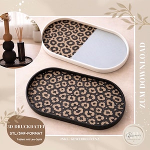 Könnte beinhalten: Zwei ovale Tabletts mit Leopardenmuster. Eines ist schwarz mit Leopardenmuster, das andere ist weiß mit Leopardenmuster und hellblauem Abschnitt. Die Tabletts sind dekorativ und für die Inneneinrichtung geeignet.