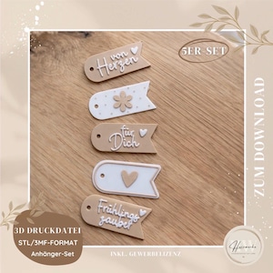 Puede incluir: Un conjunto de cinco etiquetas decorativas en beige y blanco, cada una con un diseño y texto únicos. Las etiquetas presentan frases como "von Herzen" y "Frühlingszauber". La imagen también incluye texto que indica que es un archivo de impresión 3D.