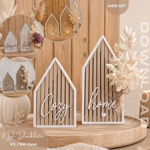 Op de afbeelding: Twee huisvormige houten decoratie-items met verticale latten en witte scripttekst Cozy en home. Het home-bordje heeft een klein wit hartje en een droogbloemstuk. De tekst 14ER-SET en DOWNLOAD is zichtbaar.