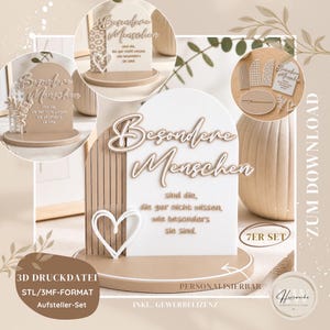 Op de afbeelding: Een set decoratieve borden met de Duitse tekst "Besondere Menschen" (Speciale mensen). De borden zijn in een neutraal kleurenpalet, met een hart en een houten lattenontwerp. De set bevat verschillende vormen en maten.