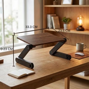 Puede incluir: Un soporte de madera marr&oacute;n oscuro para port&aacute;til con patas negras ajustables. La superficie del soporte mide 33,3 cm x 23,5 cm y se puede ajustar de 0 a 23 cm de altura. El soporte est&aacute; sobre un escritorio de madera.