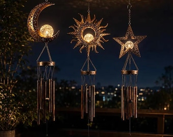 May include: Three hanging wind chimes featuring bronze-colored metal cutouts in the shapes of a crescent moon, a sun, and a star. Each shape contains a glowing crackled glass orb light, suspended above a set of metallic chime tubes and a small square pendant.