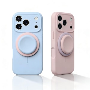 Puede incluir: Dos fundas de teléfono de silicona, una azul claro y otra rosa, con un agarre circular emergente en un color contrastante. Las fundas tienen recortes para la cámara y los botones del teléfono, y un pequeño detalle de línea en la parte inferior.