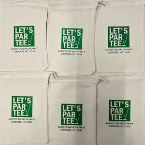 Puede incluir: Seis bolsas de algod&oacute;n de color crudo con cord&oacute;n, que presentan un gr&aacute;fico cuadrado verde con el texto LET'S PAR TEE y un icono de palo de golf. Debajo, el texto dice AARON'S BACHELOR PARTY CHEROKEE, NC | 2026 en letras may&uacute;sculas negras.
