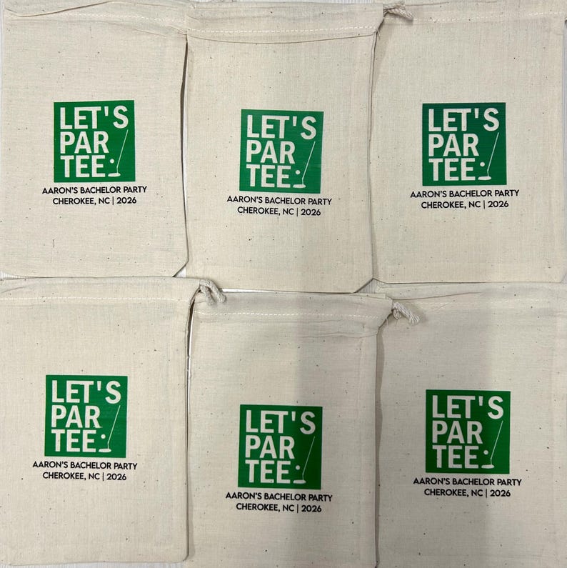Puede incluir: Seis bolsas de algod&oacute;n de color crudo con cord&oacute;n, que presentan un gr&aacute;fico cuadrado verde con el texto LET'S PAR TEE y un icono de palo de golf. Debajo, el texto dice AARON'S BACHELOR PARTY CHEROKEE, NC | 2026 en letras may&uacute;sculas negras.