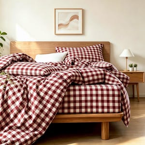 Peut inclure: Un ensemble de literie avec un motif à carreaux vichy rouge foncé et blanc sur la housse de couette, le drap-housse et les taies d'oreiller. La parure est disposée sur un cadre de lit en bois avec un oreiller blanc contre une taie assortie.