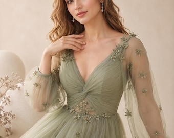 May include: A sage green floor-length dress featuring a V-neckline, long sheer bishop sleeves, and a gathered bodice. The dress is adorned with small, delicate floral appliqués scattered across the sleeves, bodice, and waistline.