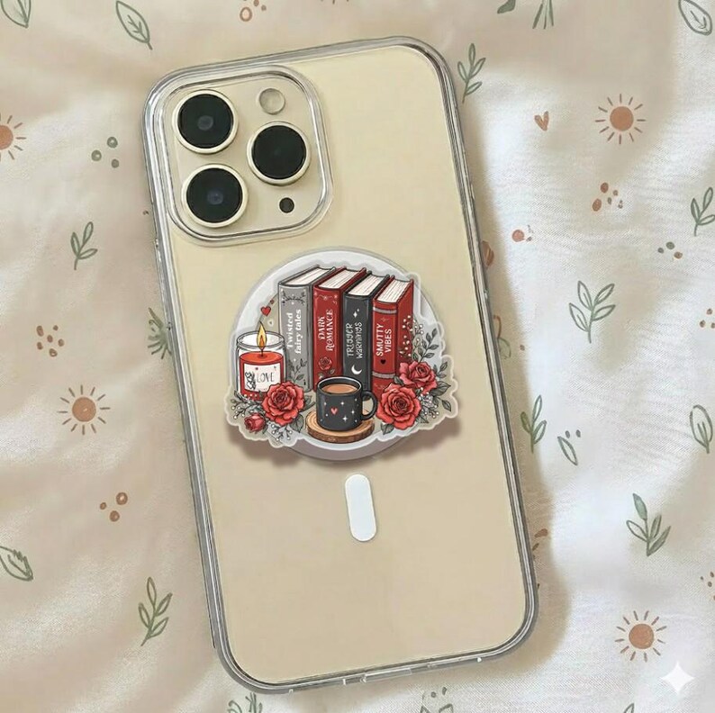 May include: A clear smartphone case featuring a sticker with a stack of four books titled Twisted Fairy Tales, Dark Romance, Trigger Warnings, and Smutty Vibes, accompanied by a lit candle, a mug, and red roses with green leaves.