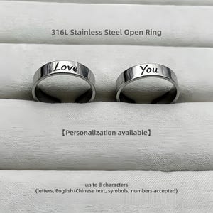 May include: Two silver-colored 316L stainless steel open rings with a polished finish. One ring is engraved with the word Love and the other with the word You. The text 316L Stainless Steel Open Ring, Personalization available, and up to 8 characters are visible.