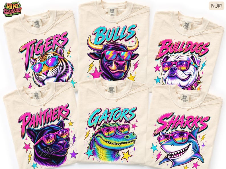 May include: Six ivory t-shirts featuring vibrant graphic prints of a tiger, bull, bulldog, panther, alligator, and shark. Each animal wears colorful sunglasses with palm tree reflections. The text Tigers, Bulls, Bulldogs, Panthers, Gators, and Sharks appears above each animal in a bold, stylized font with neon pink and blue accents.
