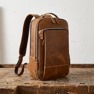 Tan leather laptop backpack with zipper compartments and padded straps