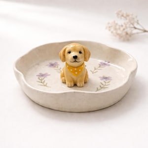 May include: A white ceramic mug with a black handle and the text "But First, Coffee" in a black, handwritten-style font. The mug is on a white surface.