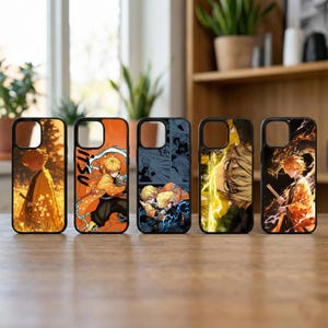 Może przedstawiać: Pięć czarnych etui na telefony z kolorowymi wzorami postaci z anime. Etui mają pomarańczową, żółtą i niebieską grafikę. Każde etui ma wycięcie na aparat i czarną obwódkę.