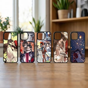 Può includere: Cinque custodie nere per telefoni con diverse illustrazioni in stile anime. Le custodie presentano scene con personaggi in abiti tradizionali, spesso con temi romantici. Presentate su una superficie di legno.