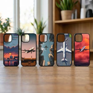 May include: Five phone cases with black borders and various airplane-themed designs. The cases feature images of airplanes in flight, against sunset and cityscape backgrounds. The cases are displayed on a wooden surface.