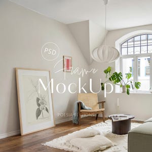 Pode incluir: Uma cena interior iluminada com uma impressão botânica emoldurada. Uma cadeira tecida, uma pequena mesa redonda e um tapete branco com almofadas estão na sala. O texto "Frame MockUp" é visível.