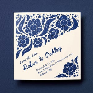 May include: A square save the date card with a cream background and dark blue floral block print design. The text reads: Save the date, Robin & Oakley, Friday, July 31, 2026, Clover & Moss Farm 14 Wheedrawing Lane, Millbrook, NY. The logo whee is at the bottom.