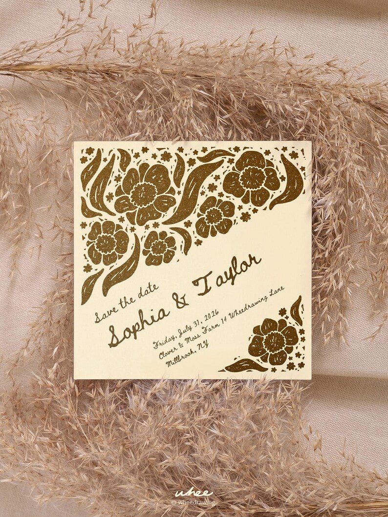 May include: A square cream-colored save the date card featuring gold floral illustrations in the corners. The text reads: Save the date, Sophia & Taylor, Friday, July 31, 2026, Clover & Moss Farm 14 Wheedrawing Lane, Millbrook, NY.