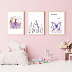 Puede incluir: Tres impresiones artísticas en acuarela enmarcadas con un marco de madera clara. Las impresiones presentan una bailarina, una inicial floral y una mariposa con texto. La paleta de colores incluye tonos de morado, rosa y dorado. Las impresiones se exhiben en el dormitorio de un niño.