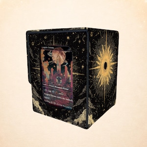 May include: Black card storage box with a gold sunburst design and a card featuring a landscape with a large moon. The box has a magnetic closure and is designed to hold trading cards. The text on the card is "Raugrin Triome".