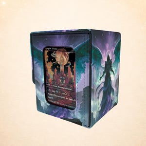 May include: A square card storage box with a fantasy art design. The box features a card with the text "Raugrin Triome" visible through a clear window. The box has a dark blue and purple color scheme with a celestial and angel theme.