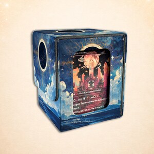 May include: A blue card storage box with a celestial design featuring clouds and stars. The box has a circular opening and displays a card with a fantasy landscape. The card reads "Island Mountain Plains".