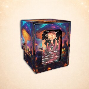 May include: A rectangular deck box for trading cards featuring a vibrant fantasy illustration of glowing mushrooms, a full moon, and a frog wearing a wizard hat. The box has a central cutout window displaying a card labeled Raugrin Triome.