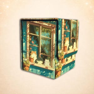 Puede incluir: Una caja de almacenamiento rectangular con una ilustraci&oacute;n impresa de gatos sentados en el alf&eacute;izar de una ventana. El dise&ntilde;o incluye marcos de ventana azules, plantas en macetas con flores rosas y varios gatos en tonos naranja, gris y blanco.